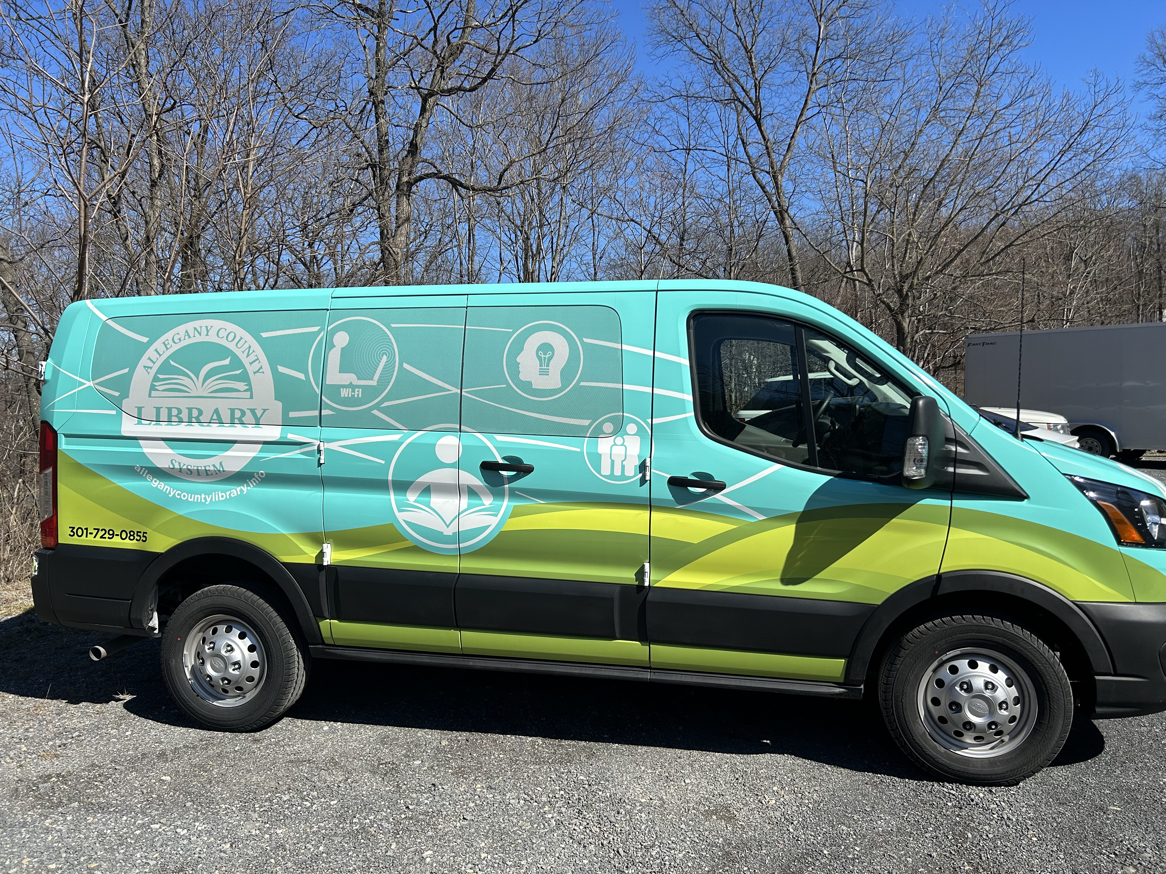 ACLS Express van.  ACLS logo and wavy lines connecting symbols of family, books, online connection, and knowledge 