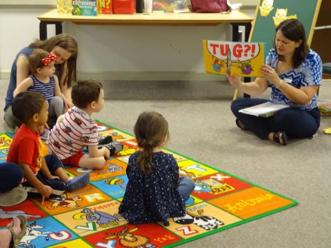 Miss Misty reading a story to children sitting on the floor 